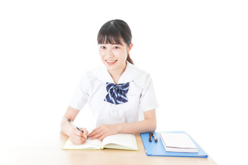 机で勉強をする制服姿の女子学生