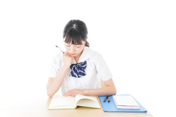 机で勉強をする制服姿の女子学生