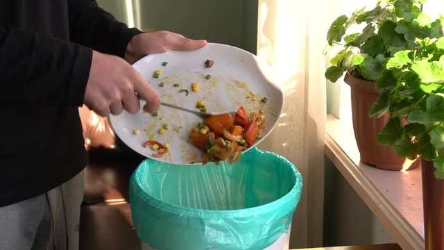 Food Waste Reduction. A man throws baked vegetables in the bin. The restaurant industry has a big food waste problem. Unused food in restaurants being disposed, recycled, or is donated