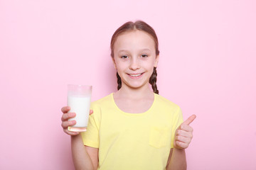 Child with glass of milk on a colored background.