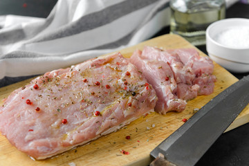 piece of pork tenderloin with spices on a cutting Board, knife, towel, meat