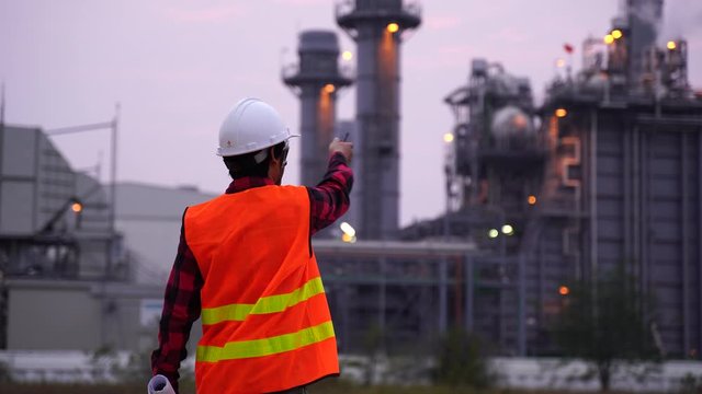 Engineer with a coal power plant in the background, Thailand.