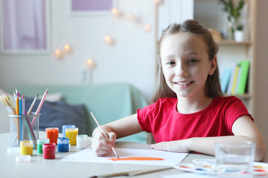 Cute little girl draws paints at home.