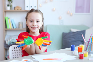 Cute little girl draws paints at home.