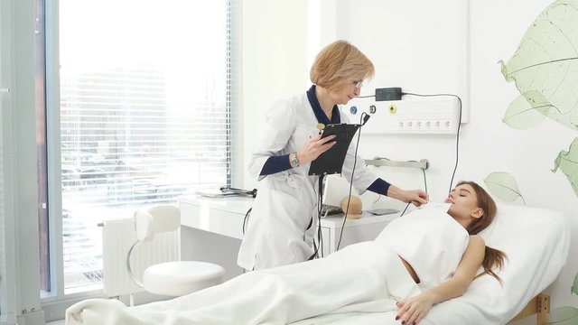 Beauty salon. Young attractive girl in a cosmetic salon lying on the table takes electro therapy.