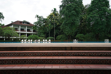Obraz premium Stair steps to public swimming pool with building among green nature and cloudy sky