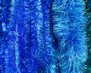 Fluffy foil blue tinsel, close-up background backdrop. Hanging aquamarine garland made of polyethylene silver foil, Christmas decoration, background for design