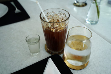 Close up glass of iced black Americano coffee with spring water and sugar syrup