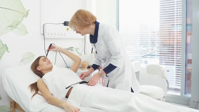 Beauty salon. Attractive girl in a cosmetic salon lying on the table takes electro therapy.