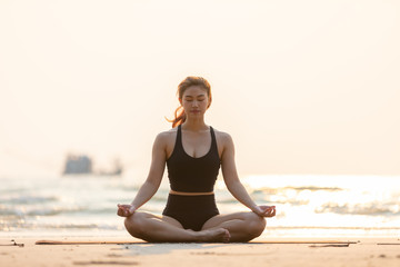 Fototapeta na wymiar woman practice yoga lotus pose to meditation with summer vacation on the beach feeling so happiness and cheerful,Travel in tropical beach in Thailand,vacations and relaxation Concept