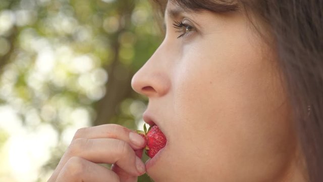 Vitamin and berry diet for women. beautiful girl eating sour strawberry wrinkle and smiling. close-up. happy girl eating strawberries in summer in garden. Delicious strawberry dessert.