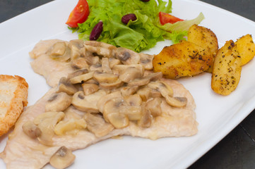 Stewed mushrooms with fish fillet, salad, fried potatoes and croutons, close-up. Tasty traditional italian food