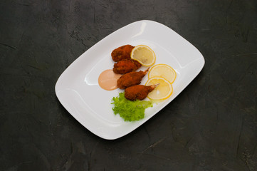 Crab claws fried in batter with lemon, lettuce and tasty sweet and sour sauce. Festive dish of Italian cuisine