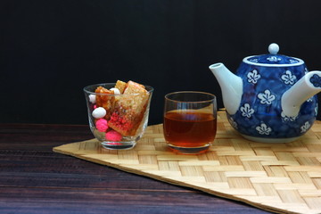 Chinese candy or dessert in glass with Chinese tea set isolate on black background.