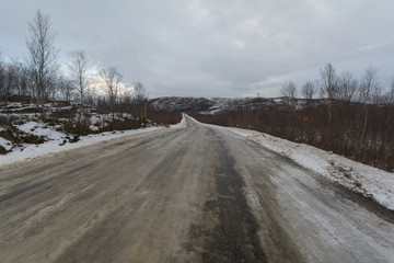 Obraz premium The dirt road is covered with ice .The sky is covered with clouds.