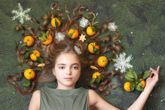 The image of a beautiful girl with tangerines in her hair under the falling snow