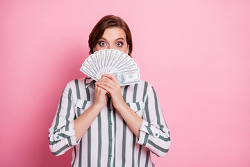 Portrait of amazed shocked girl hide cover her face with money fan she get from deposit credit bank wear modern clothing isolated over pink color background