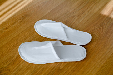 Couple new eco-friendly fabric disposable slippers lie on wooden floor