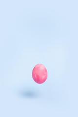 One flying pink chiken egg on a blue background.