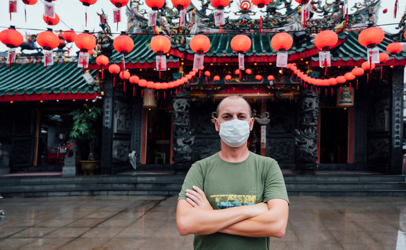 Man with mask next to a Chinese temple. Virus concept