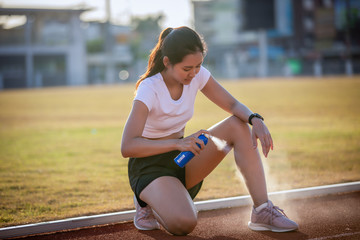 Asian Sports women using freezing spray for treating injured sportwomen's knee and leg  after run