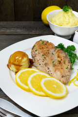 Baked chicken breast with lemon for fresh in white dish on wooden table.
