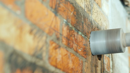 Steel drill drills a hole in a brick wall
