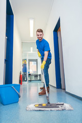 Cleaner man mopping the floor in a hall