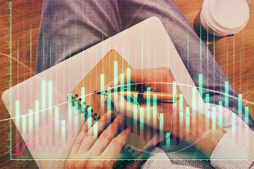 Double exposure of hands writing in notepad with stock market chart.