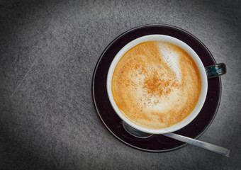 cappuccino coffee cup with spoon top view on grey table, filtered image
