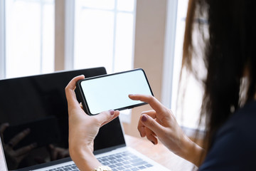 Close up of a woman using white screen smart phone mockup at home.