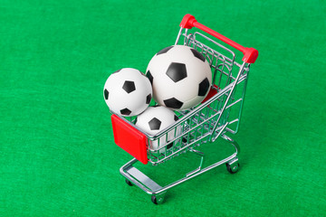 Soccer balls in shopping cart on foorbal field