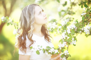 light portrait of an apple tree, girl portrait of a high key, spring mood freshness and purity blonde with long hair in a blooming park in the spring