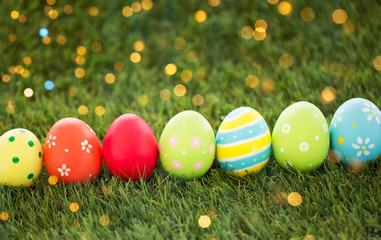 easter, holidays and tradition concept - row of colored eggs on artificial grass