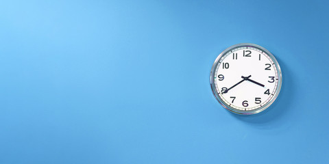 Close-up wall clock set on blue background. The concept of The time is going on. Copy space