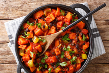 Chili sweet potatoes and black beans with tomatoes, celery close-up in a pan. Horizontal top view