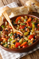 Three bean soup with vegetables served with bread close-up. vertical