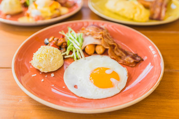 Fried egg with bacaon sausage ham vegetable potato in plate