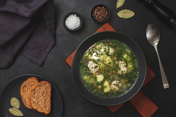 Chicken and potato chowder soup with pepper and carrot in black bowl