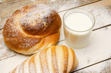 glass of milk, loaf, loaf on a wooden background with flour. Balanced diet, protein and carbohydrates, cereals