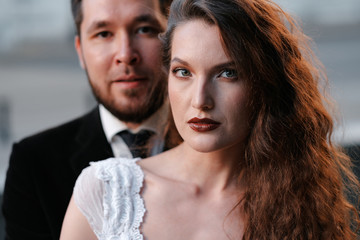 Beautiful wedding couple of newlyweds - red-haired young bride in a white dress and a bearded groom in a black suit. Amazing smiling wedding couple. Pretty bride and stylish groom.