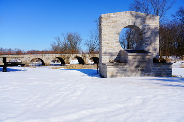 Stone Arch way walking path bridge at Riverside park in St. Cloud, Wisconsin covered in snow during Winter season. 