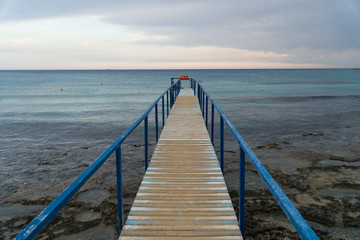 Fototapeta na wymiar Old wooden pier leading to the sea on Cyprus.