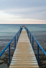 Fototapeta na wymiar Old wooden pier leading to the sea on Cyprus.