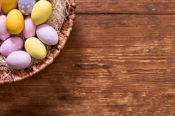 Happy Easter! Basket with Colorful Decorated Eggs Over Rustic Wooden Background.