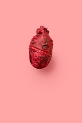 Red anatomical rubber heart on a pink background