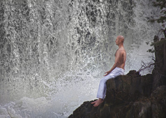 Buddhist. Bald man. Meditation in the mountains against the backdrop of a waterfall. Prayer.