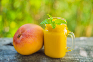 Mango smoothie in a glass Mason jar and mango on the old wooden background. Mango shake. Tropical fruit concept