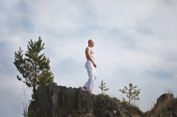 Buddhist. Bald man. Meditation in the mountains against the backdrop of a waterfall. Prayer.