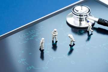 Miniature people doctors with protective suit and mask working on chemical compound on blackboard with the headline COVID-19, Corona virus medicine research, COVID-19 flu outbreak pandemic concept